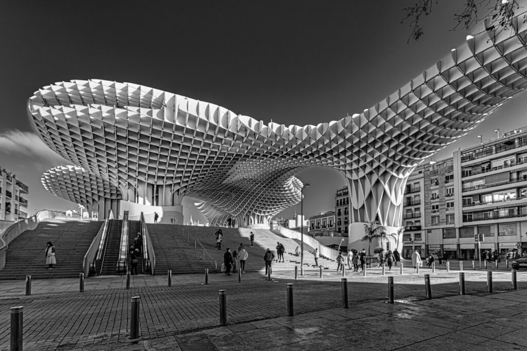 A stunning black and white photograph of the Metropol Parasol with people in Seville.