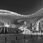 A stunning black and white photograph of the Metropol Parasol with people in Seville.